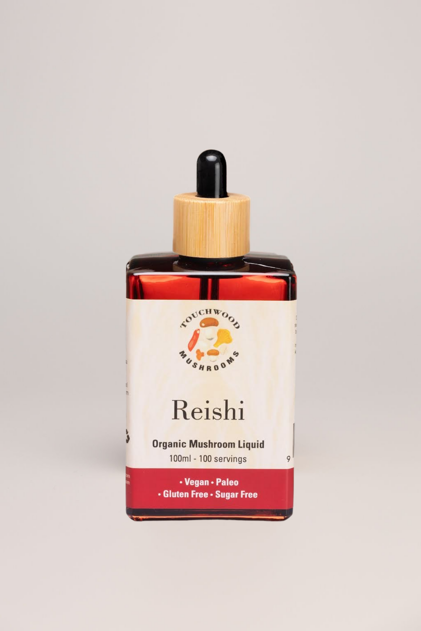 Bottle of Reishi organic mushroom liquid with a wooden dropper on a light grey background