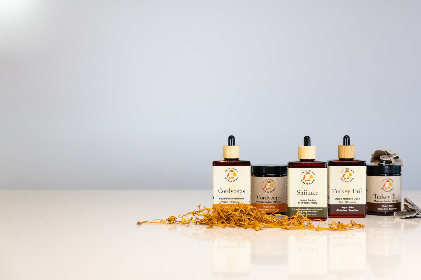 Collection of mushroom tincture bottles with visible labels on a reflective surface.