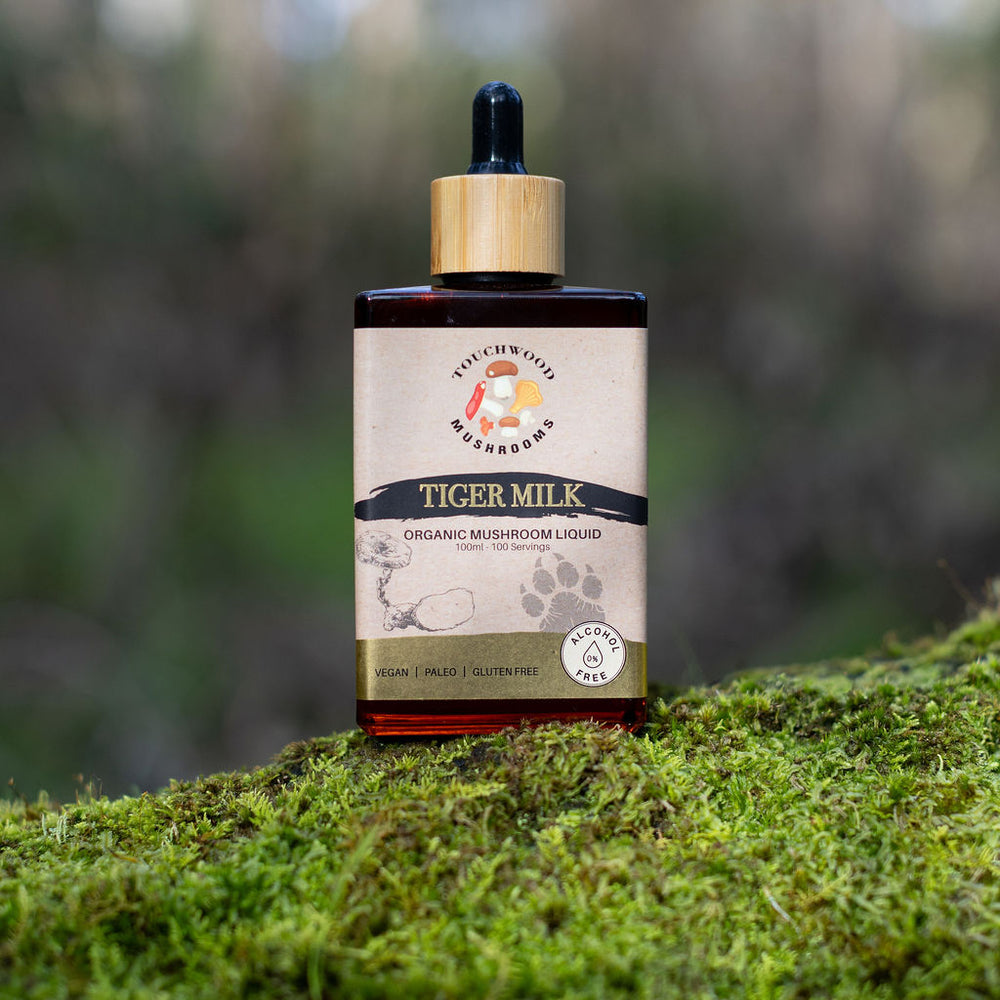 Bottle of Tiger Milk Mushroom Liquid on a mossy surface with a blurred natural background