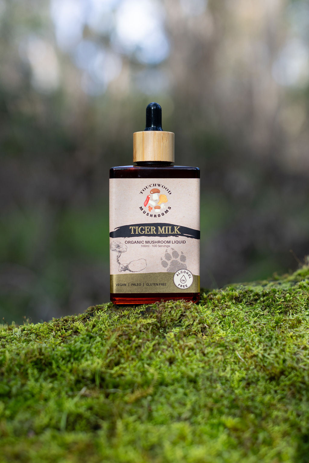 Bottle of Tiger Milk Mushroom Liquid on a mossy surface with a blurred natural background