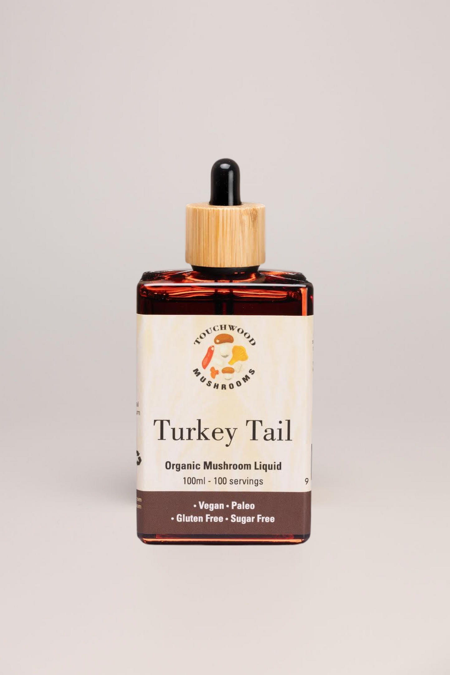 Bottle of Turkey Tail Organic Mushroom Liquid with a dropper on a grey background